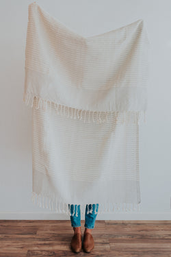  Person holding Bon Ton Studio Mila Turkish Towel in Dove Grey color in front of wall