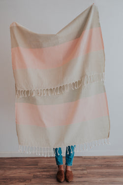 Person holding Bon Ton Studio Flora Turkish Towel in Salmon color in front of wall