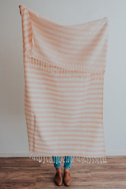 Person holding Bon Ton Studio Ulla Turkish Towel in Salmon color in front of wall