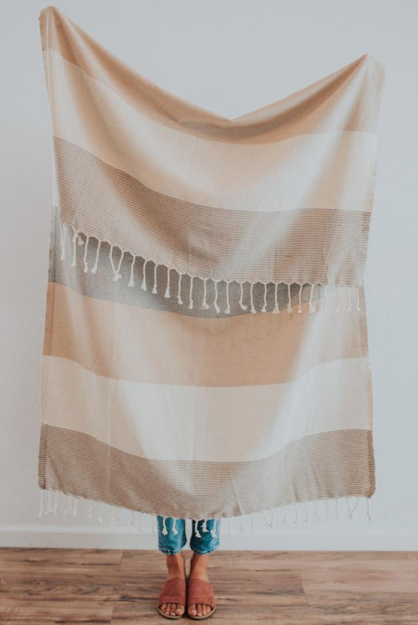 Person holding a Bon Ton Studio Turkish Towel in front of wall in studio